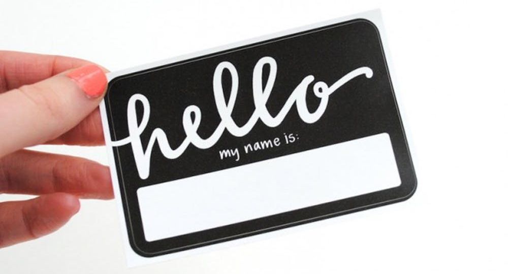 Hand holding black and white "Hello my name is" nametag