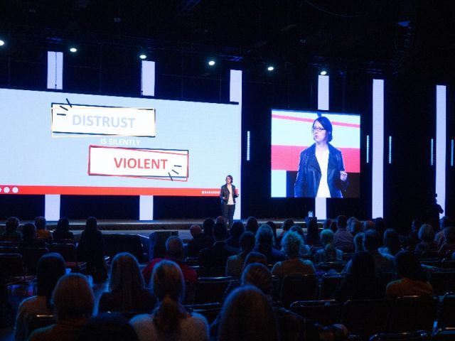 Sarah Noll Wilson speaking on stage to a group of people