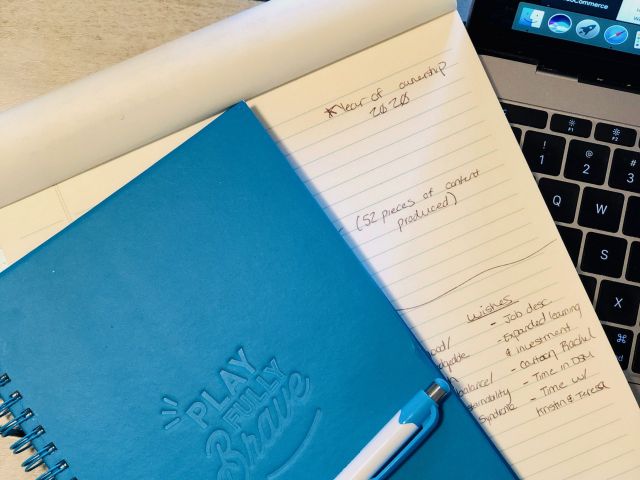 Blue Play Fully Brave notebook on top of notepad and laptop