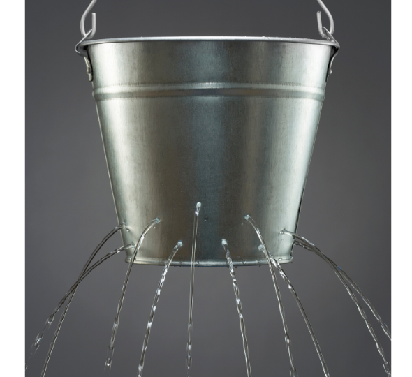 Silver bucket with holes in it spilling out water