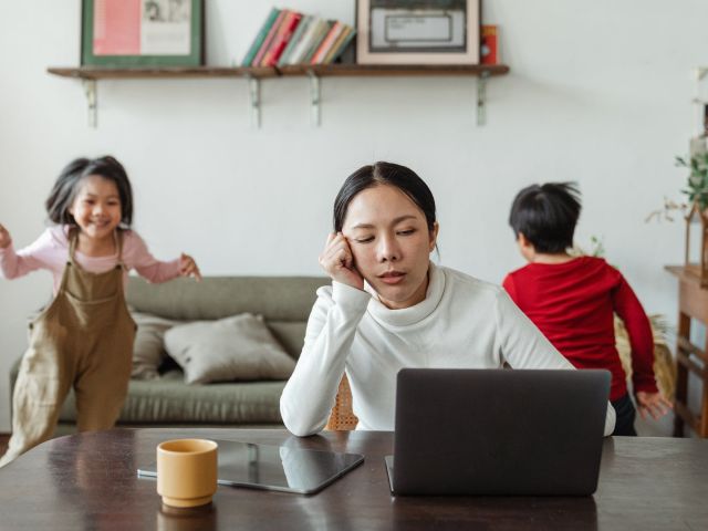 Person sitting at a computer with two children in the background