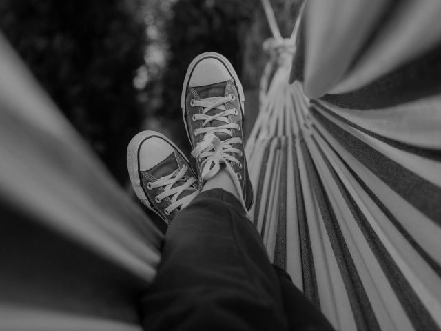 Black and white photo of person's feet in a hammock